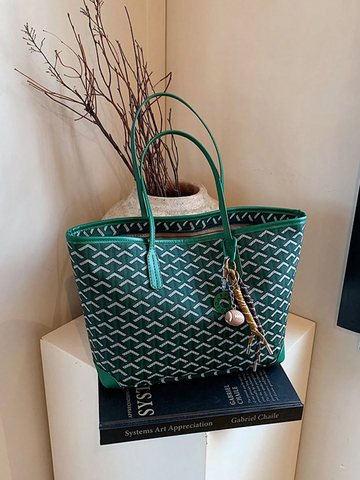 Torebka GeoLuxe w kolorze zielonym na stole z książkami